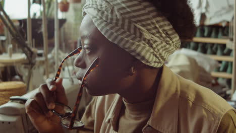 pensive african american woman in shoemaker workshop