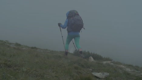 rocky-alpine-peaks,-landscape-of-a-slovakian-tatra-mountains,-female-hiker-walking-on-a-trail,-camera-pan-from-right-to-left-to-follow-the-movement