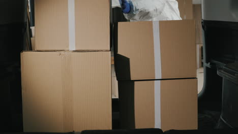 a worker in a protective suit unloads boxes of medicines