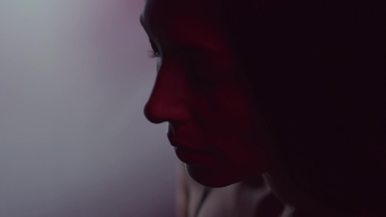 Primer plano de perfil de mujer en estudio oscuro con luz de neón atmosférica