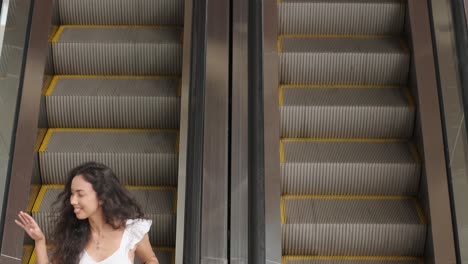 young woman walks with colorful shopping bags around a shopping mall an escalator