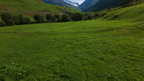 Drone-flying-over-green-meadow-of-Furka-pass-in-summer-season,-Switzerland