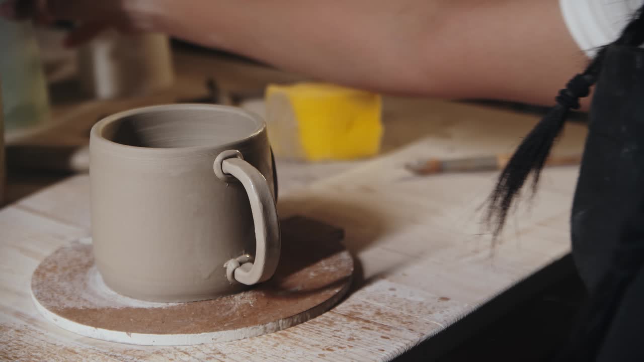 mujer joven alfarero rociando agua en los bordes del mango y una copa