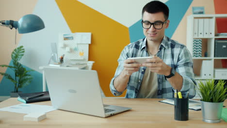man playing mobile game at office desk