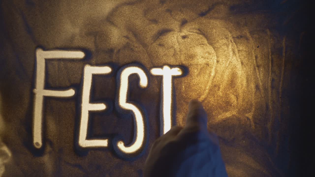 FESTIVAL Inscription. Sand On Illuminated Glass