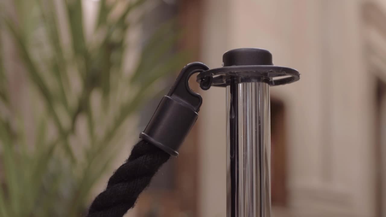 empleado enganchando un poste de cuerda para bloquear el acceso.