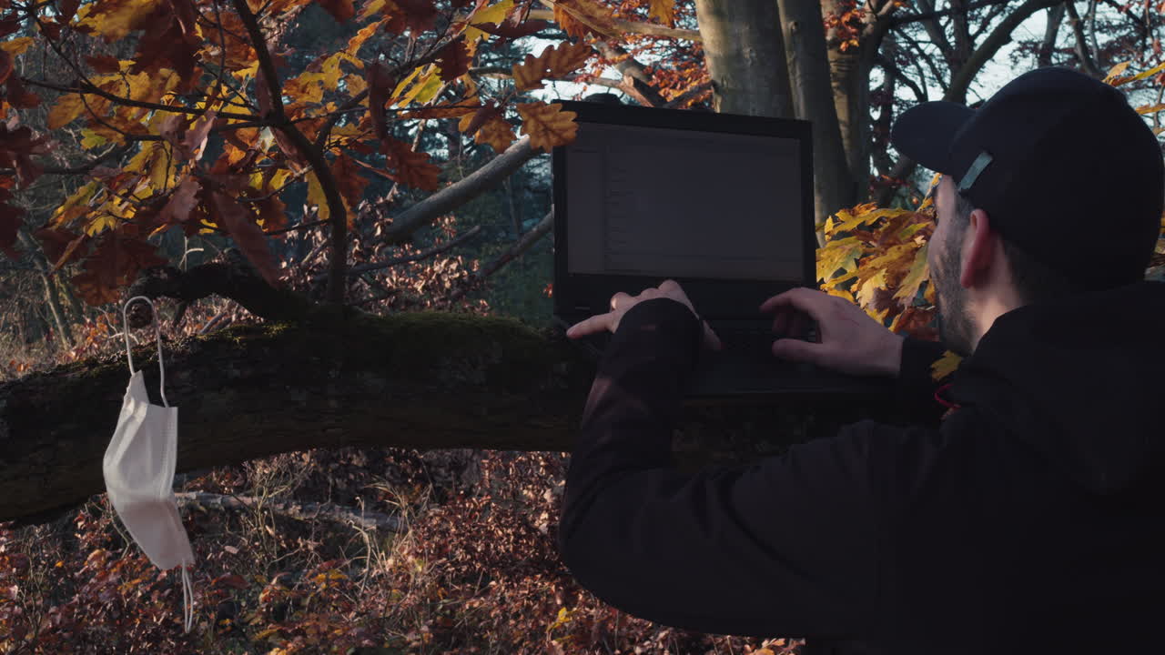 Male using laptop in forest during covid pandemic, workaholic concept
