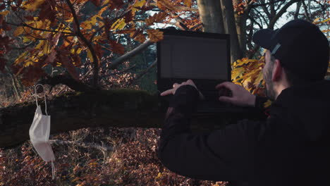 hombre usando una computadora portátil en el bosque durante la pandemia de covid, concepto de adicto al trabajo