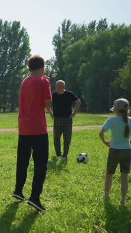 un abuelo conduce a sus nietos en una actividad deportiva al aire libre, los niños se paran con las manos en la cintura, preparándose para saltar, mientras disfrutan de un día soleado en un campo cubierto de hierba