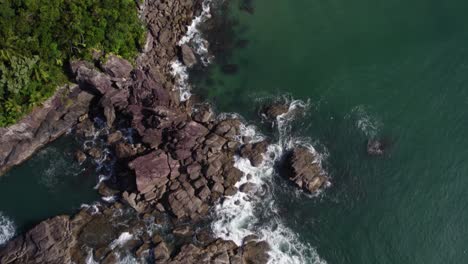 aerial view over a rocky bay towards a beach, in costa verde, brazil - tilt, drone shot