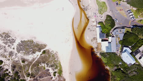 Top-down-aerial-over-Onrus-lagoon-and-white-beach-toward-ocean-along-coastline