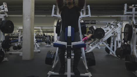 Schwarzer-Männlicher-Bodybuilder-Strongman-Athlet-Hebt-Schwarze-Gewichte-Mit-Der-Linken-Hand-Auf-Sportgeräten-In-4k