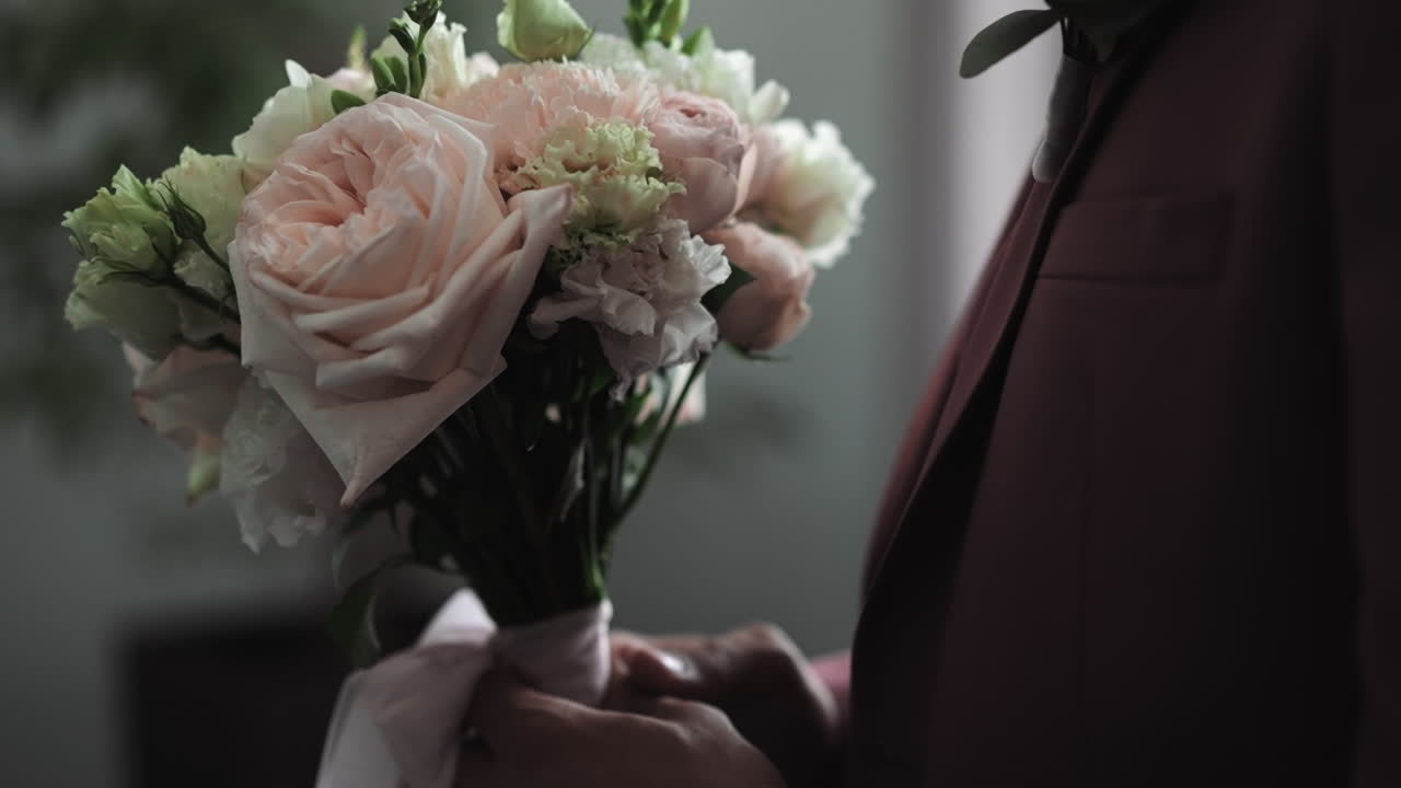 우아 한 스 ⁇ 세도 를 입은 신랑 은 결혼식 에서 꽃 꽃다발 을 들고 있다