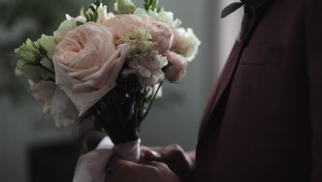 Groom-in-elegant-tuxedo-holds-flowers-bouquet-at-wedding