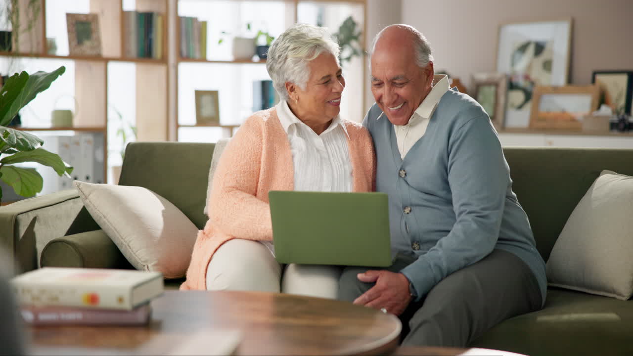 Äldre par njuter av laptop i soffan
