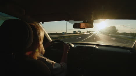 middle-aged female driver drives car in setting sun 2