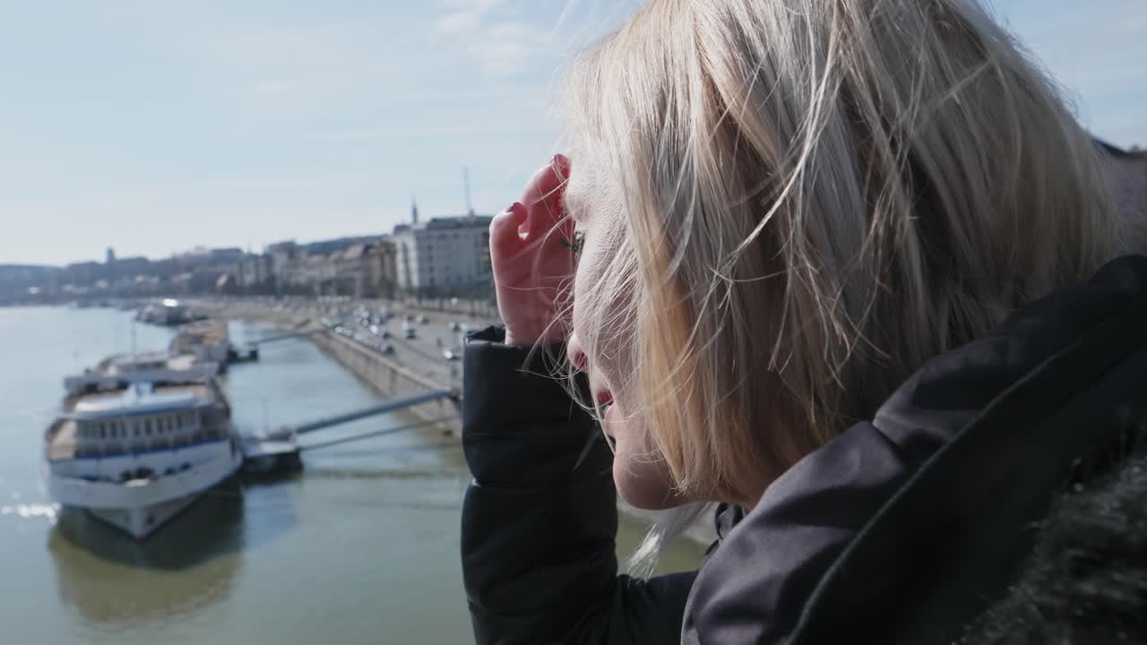 Social distancing concept. Lonely woman on the Margaret bridge looking across the Danube river and stopped ferry traffic