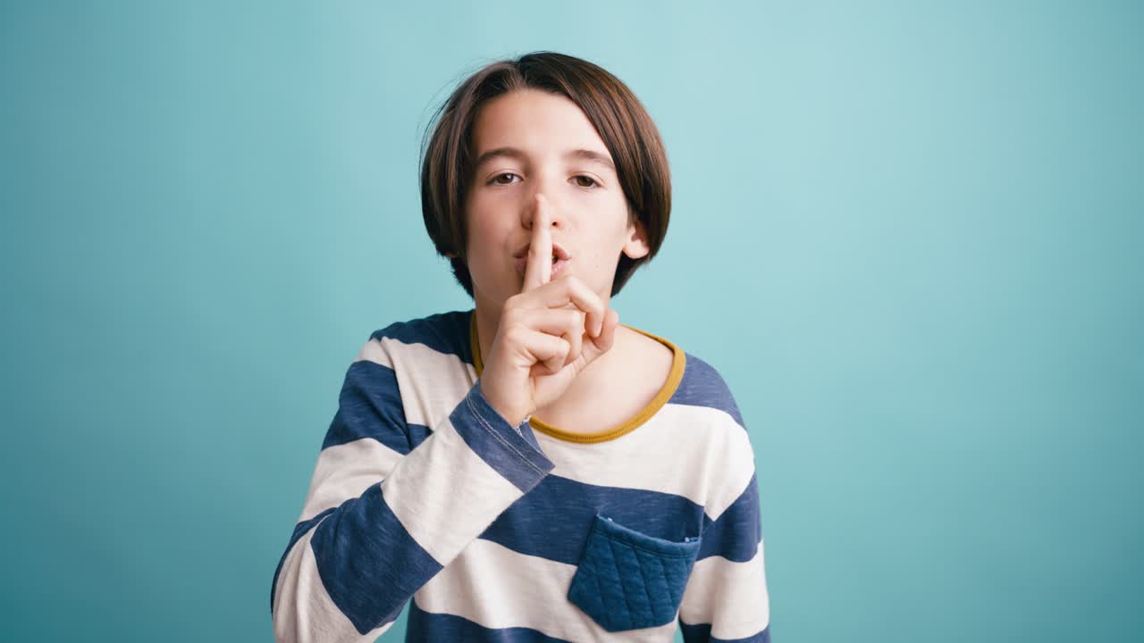 唇に指をあててシーッというジェスチャーをする少年