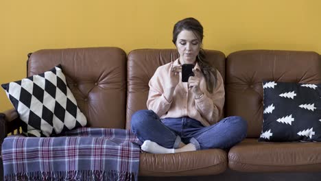 woman sitting on a couch using a phone