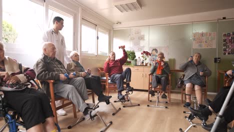 senior men and women doing pedal exercises and lifting dumbbells at rehabilitation center