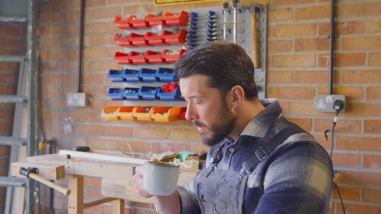 retrato de un hombre sonriente con mono en un taller de garaje con bebida caliente