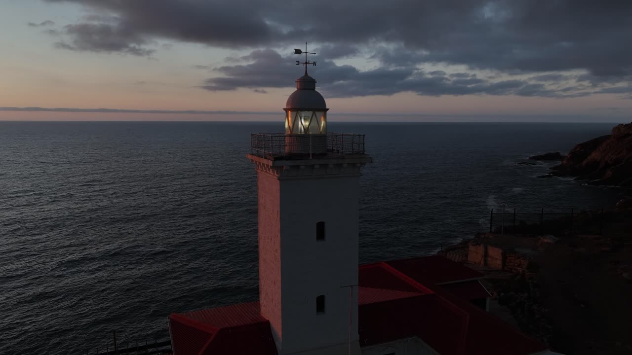 Cerchi aerei faro in mattoni su una scogliera con vista sull'alba dorata sul mare