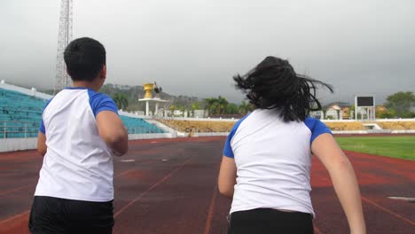 back view of boy and girl running at stadium