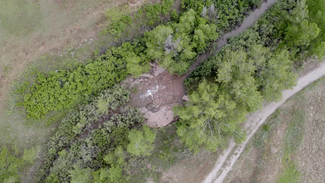 вид с воздуха на небольшой ручей с маленьким водопадом посреди большого открытого поля