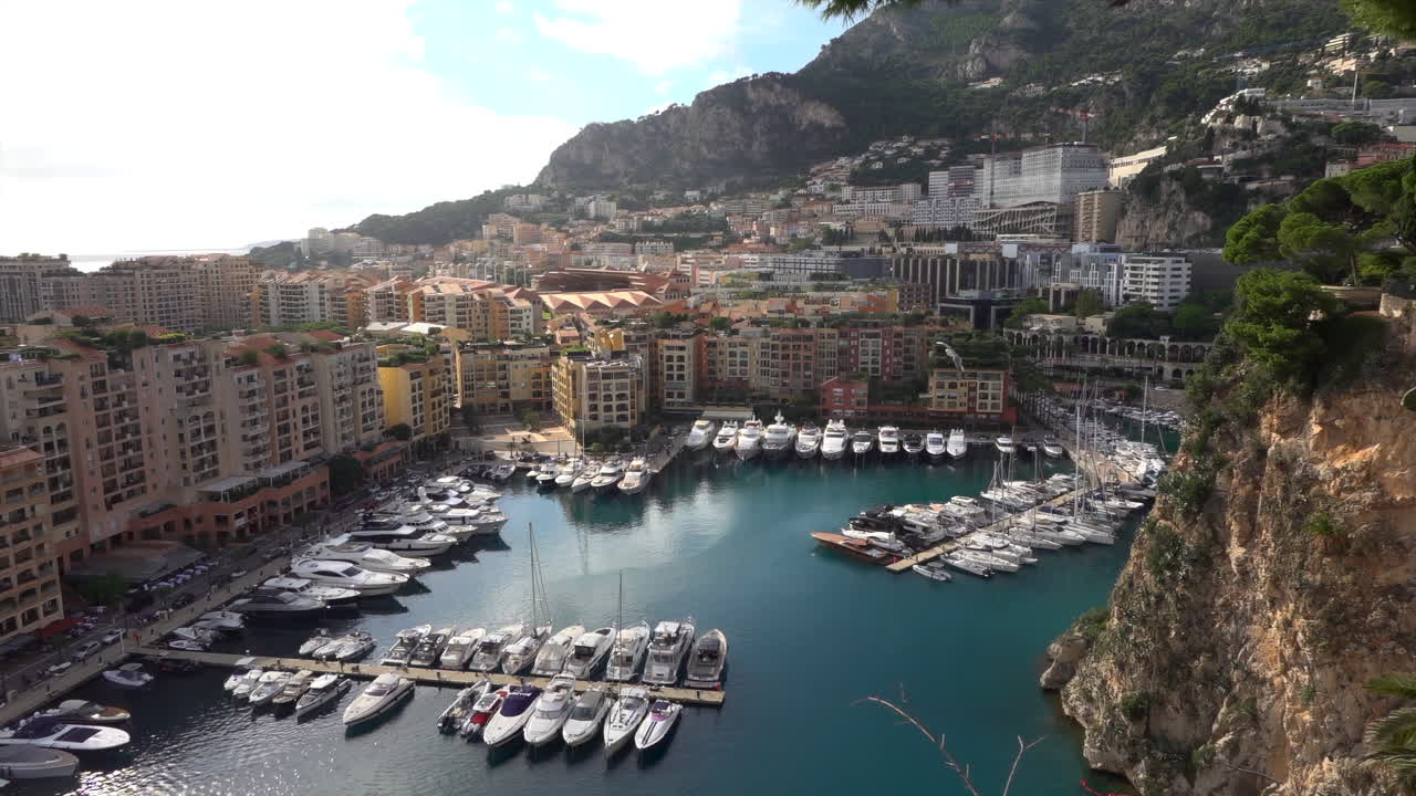 Vista dall'alto di Port de Fontvieille a Monaco, con edifici colorati, yacht di lusso e il paesaggio montuoso circostante