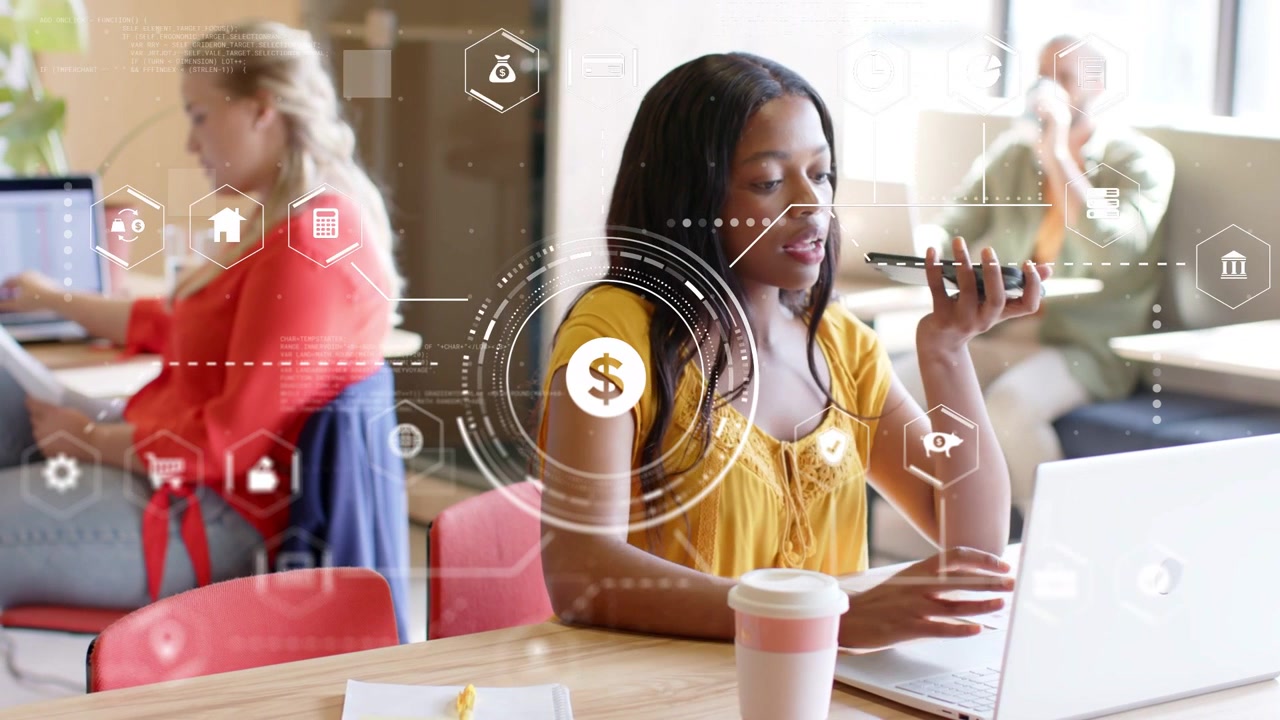 Woman in yellow typing on laptop, AR finance HUD overlaying woman, causing speaking to phone