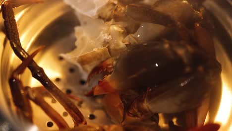 crab being cooked in a pot over flame