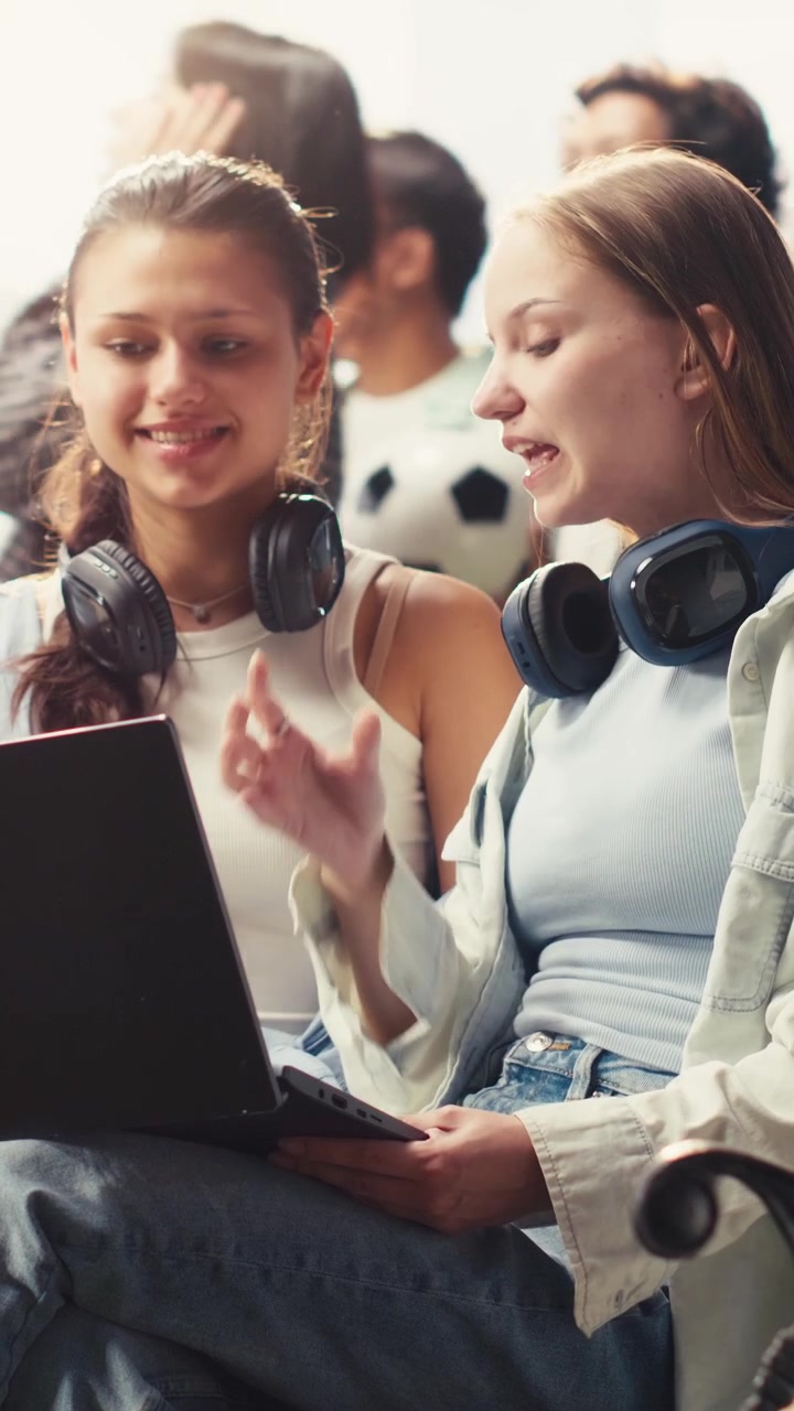 Video verticale: Compagne di classe che collaborano al laptop sedute su una panchina del campus