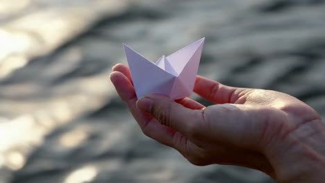 paper boat in hand by water