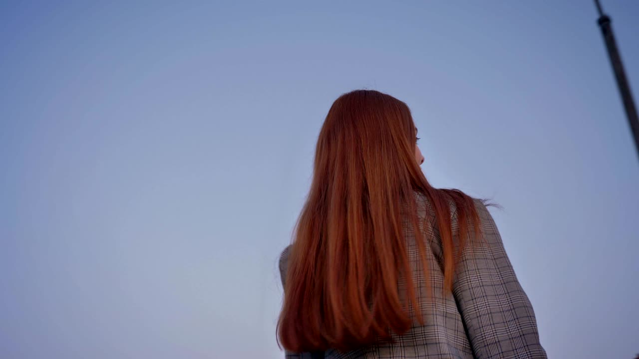 긴 은 머리카락을 가진 아름다운 젊은 여성이 카메라를 바라보고 돌아서고, 위의 파란 하늘, 주변을 돌아다니며, 낮은 각도