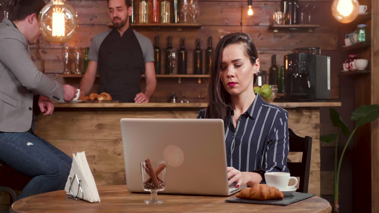 Kvinde arbejder på bærbar computer på café