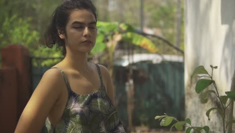 pretty young indian woman looks very mysterious as she faces the camera in the middle of a garden