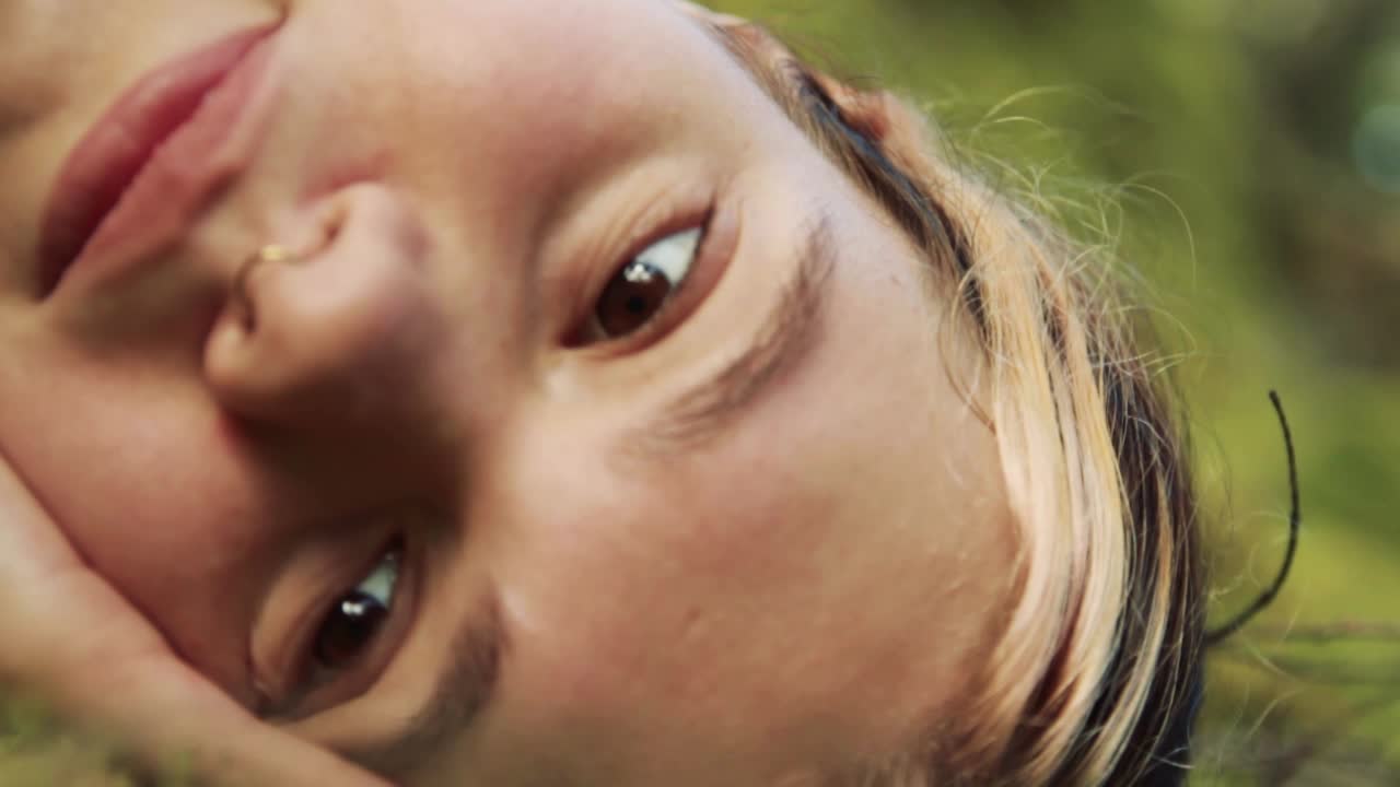 una hermosa joven adulta yace en un bosque verde y cubierto de musgo mientras disfruta del sol y la calma