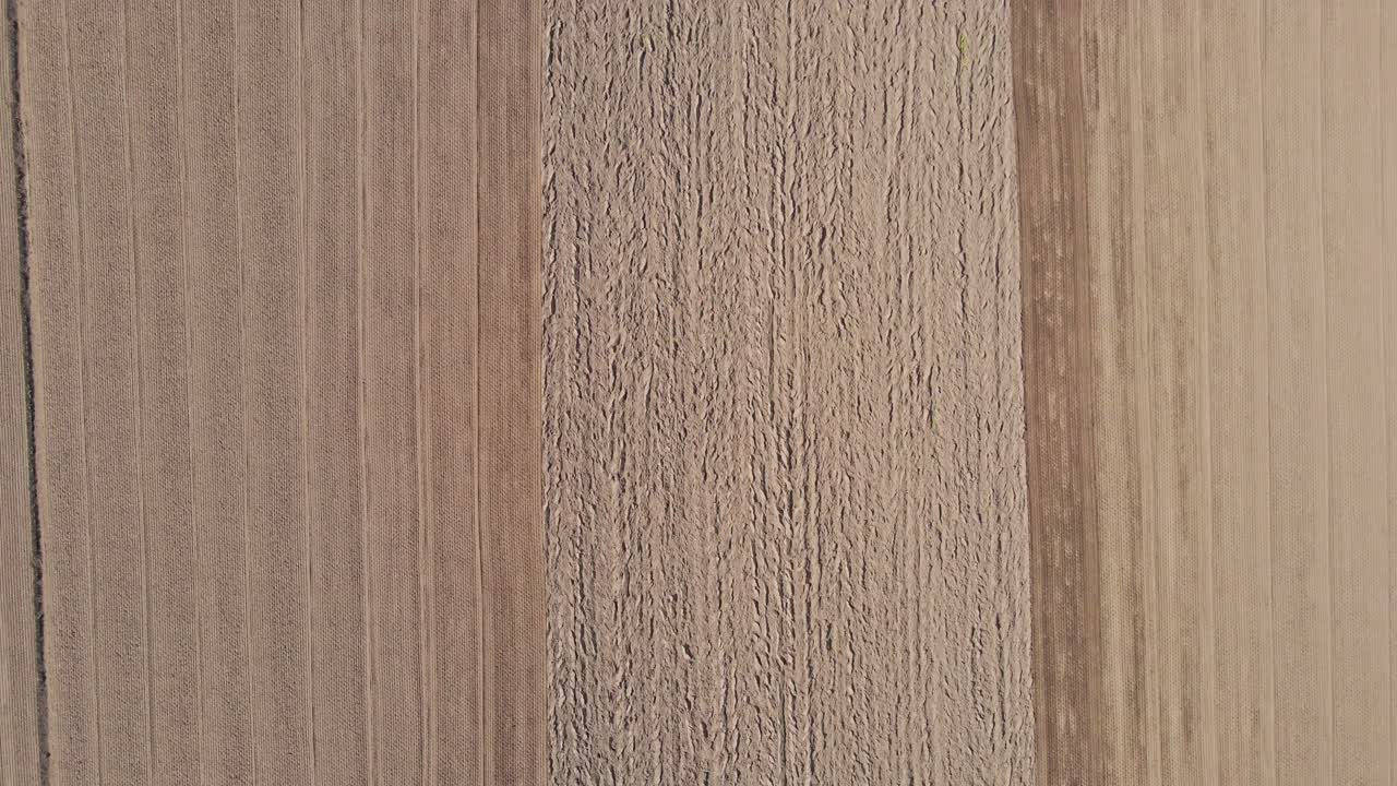 hermosa antena de pistas en una parcela vacía de tierras de cultivo y revelando un tractor de trabajo arando el prado