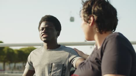 Young African American man talking to his female friend outdoors