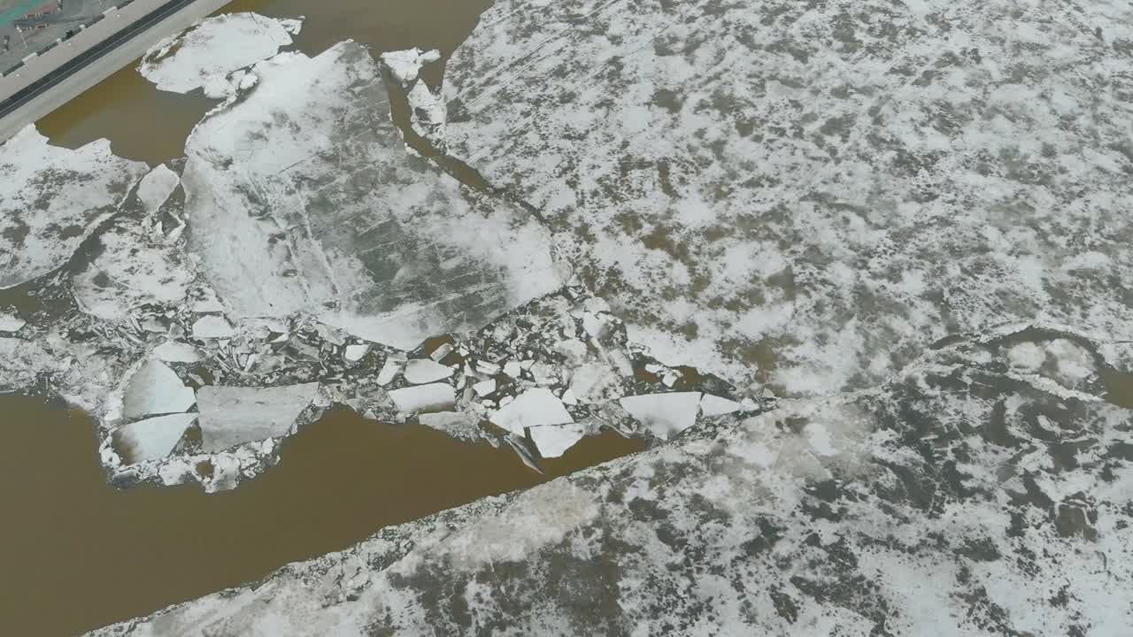 полузамерзшая глубокая река на берегу с серой застройкой