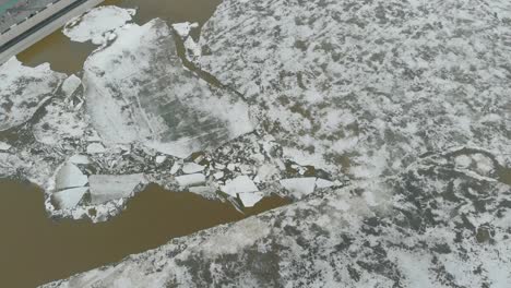 half-frozen-deep-river-at-bank-with-grey-construction