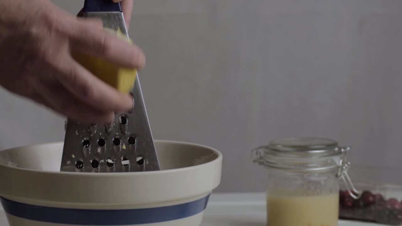 Hand grating juicy lemon in kitchen medium shot