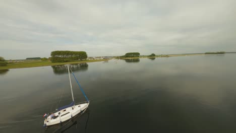 Vuelo-Aéreo-De-Drones-Sobre-Un-Velero-En-Aguas-Tranquilas-Del-Lago-Veerse-Meer