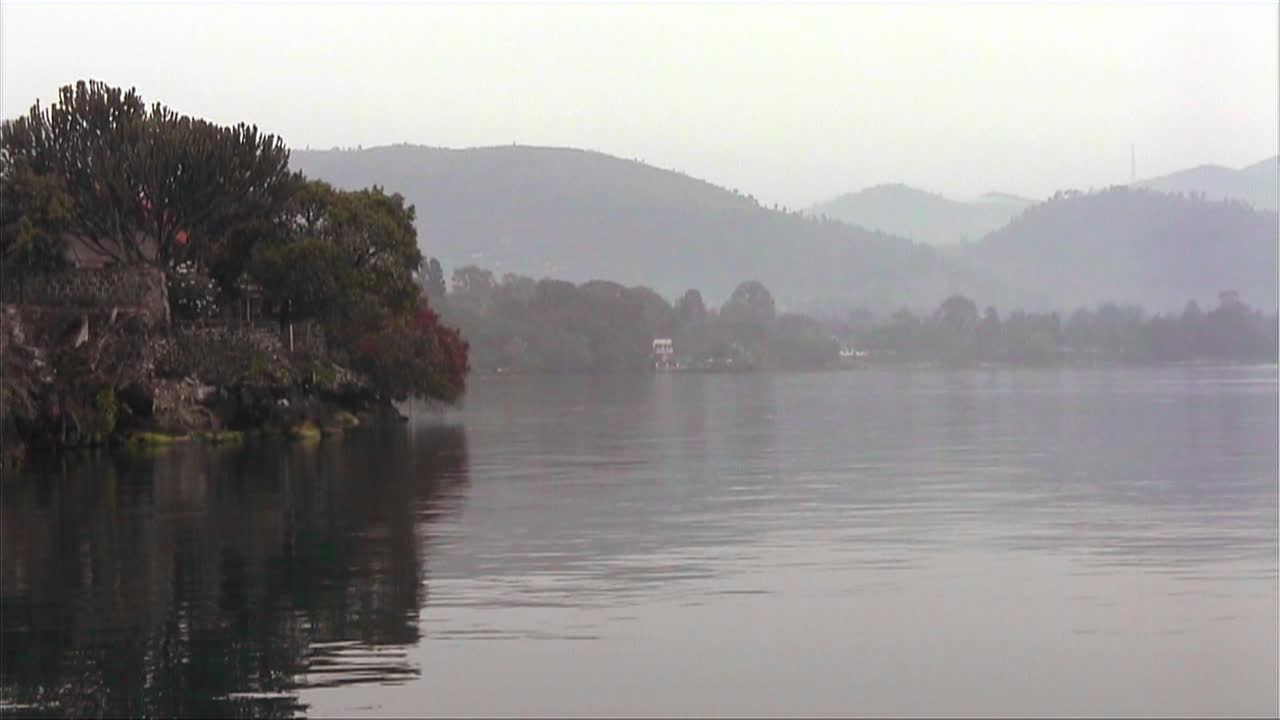 un lago tranquilo en un campo rural con casas con techo de paja visibles en la orilla