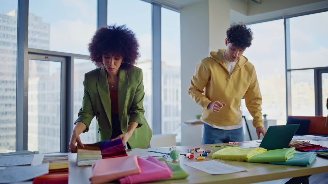 Two fashion designers choosing fabric samples in atelier office. Creative team