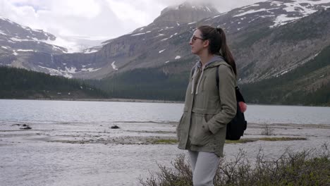 young girl with hands in the pockets walking on the shore of bow lake