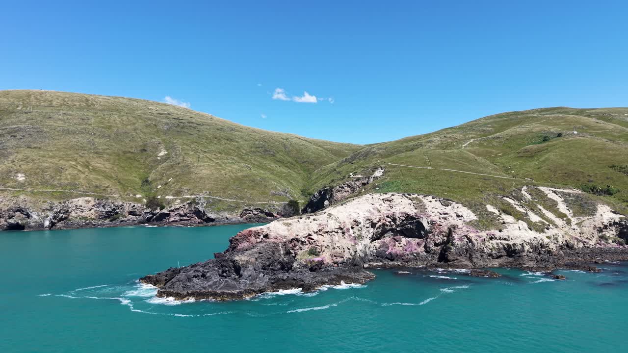 Flying sideways past finger of land with people fishing and others on walkway (Godley Head Walkway, Canterbury, New Zealand)