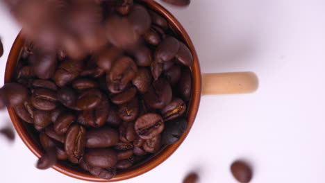 coffee beans being poured into a cup on a white background