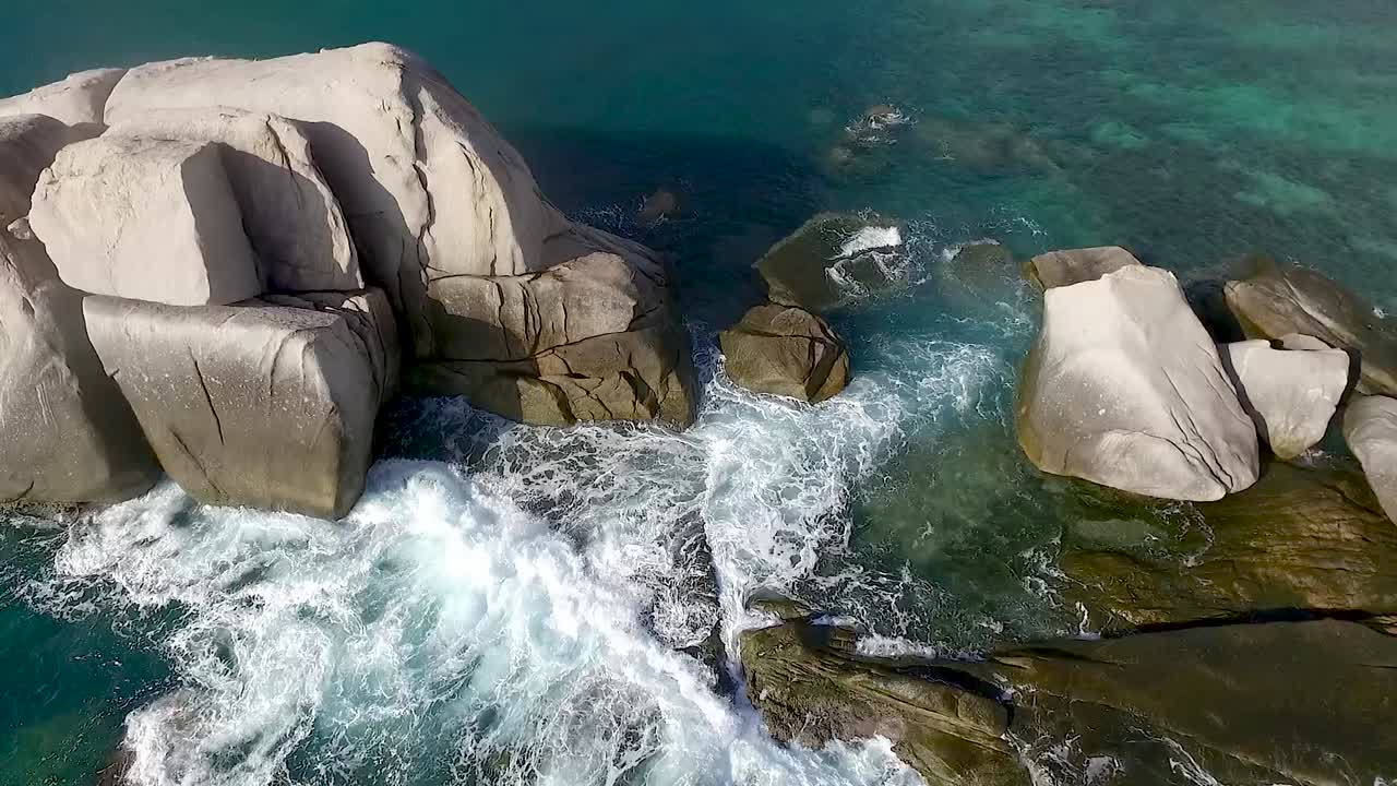 슬로우 모션 공중 파도가 바위에 부서지고 카메라가 부드럽게 위로 기울어집니다.