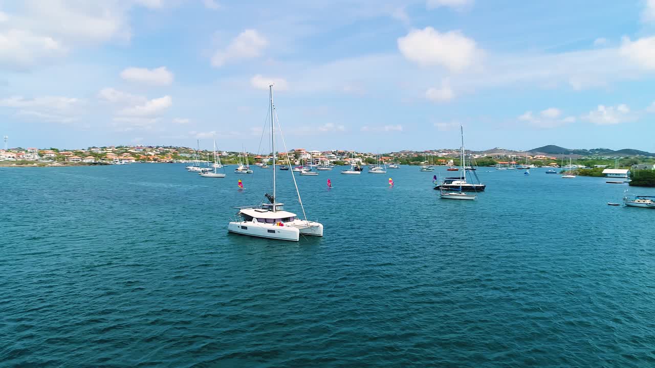 paralaje de órbita aérea alrededor de un catamarán anclado en las aguas españolas de curazao en un hermoso día de cielo azul